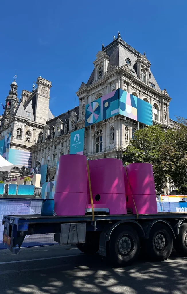 Lapee 11 Lapee purple and blue portable urinals on a trailer against a bright sky, with vibrant event branding in the background.