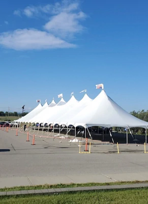 Large white event tent setup in Calgary, Alberta with clear walkway lines, spanning canopy sections under a blue sky.