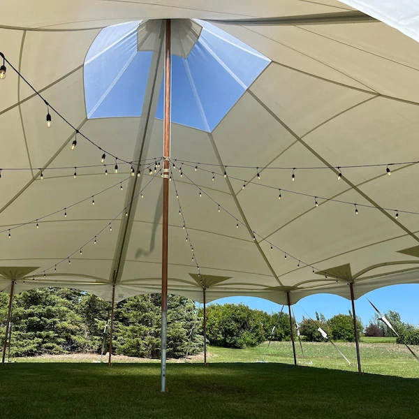 Beige Northern Light sailcloth pole tent interior with a skylight opening and decorative string lights across the canopy.