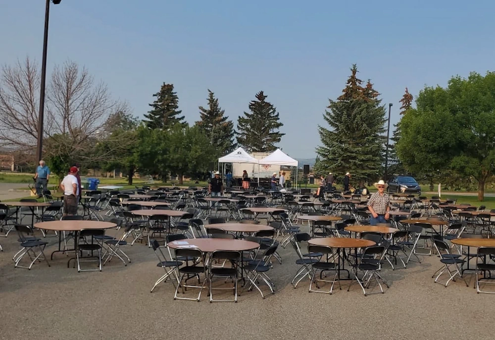 Rows of chairs and round tables set up on an outdoor gravel area near the white tent for Harvest Hills Church special event in Calgary.